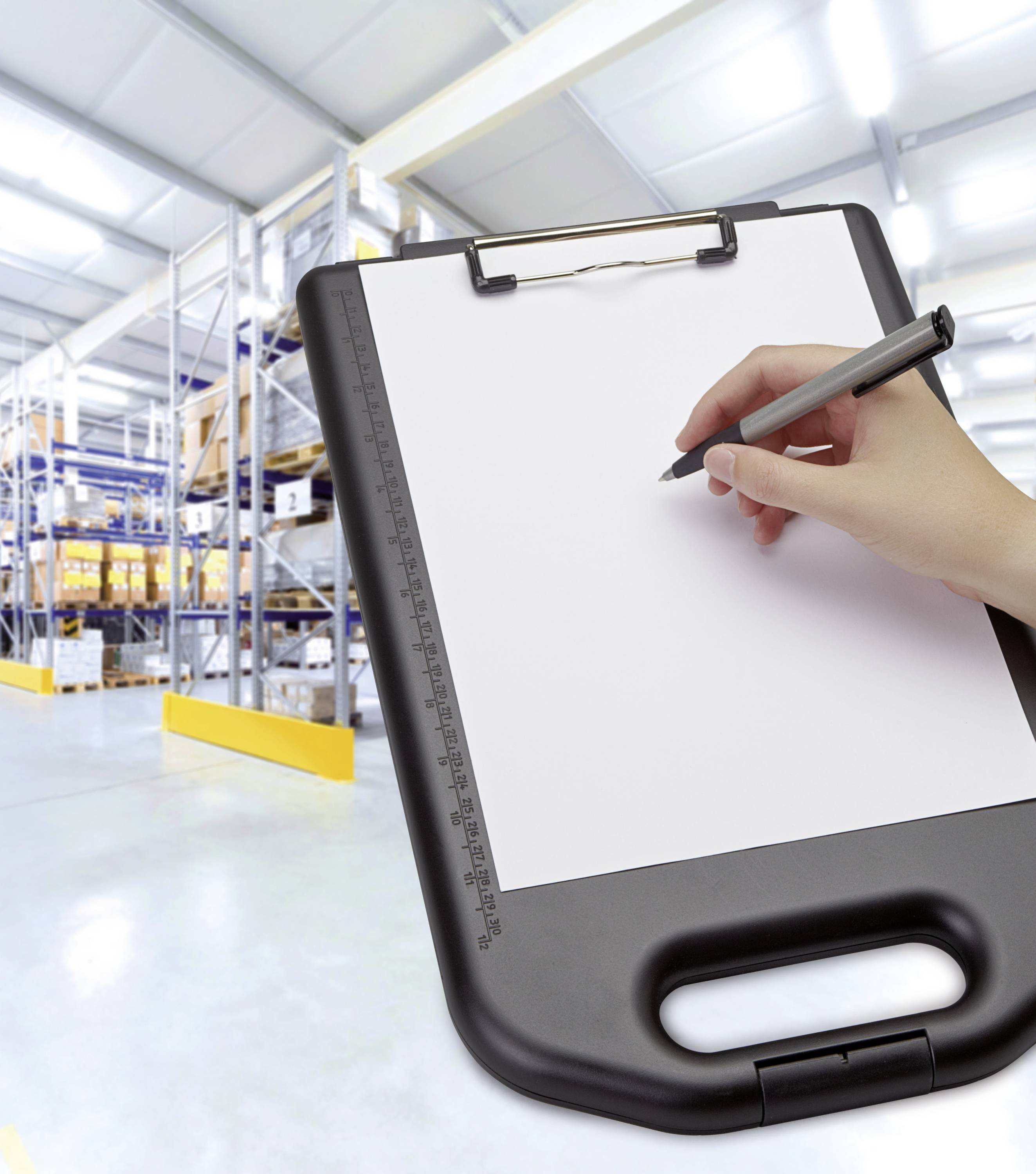 Een hand schrijft met een pen op een klembord voor een magazijn met rekken vol dozen.