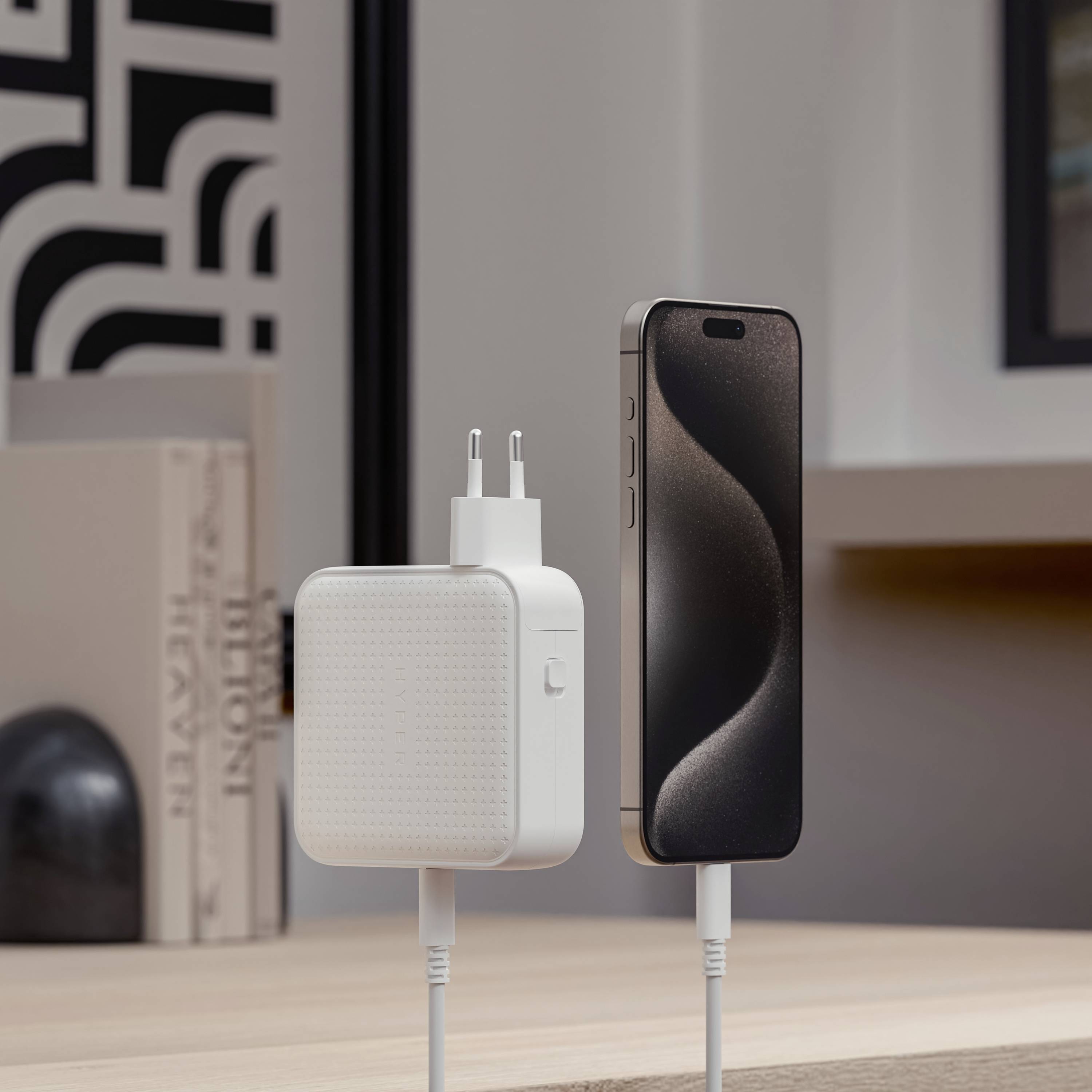 Een modern smartphone wordt via een kabel verbonden met een oplader die op een tafel in een stijlvolle ruimte staat.