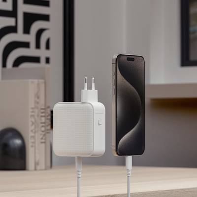 Een modern smartphone wordt via een kabel verbonden met een oplader die op een tafel in een stijlvolle ruimte staat.