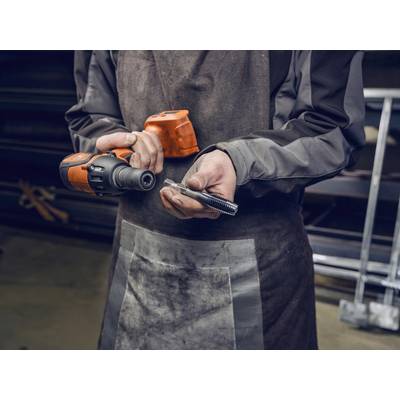 Een persoon in werkkleding houdt een elektrische boormachine in zijn rechterhand en een schroef in zijn linkerhand.
