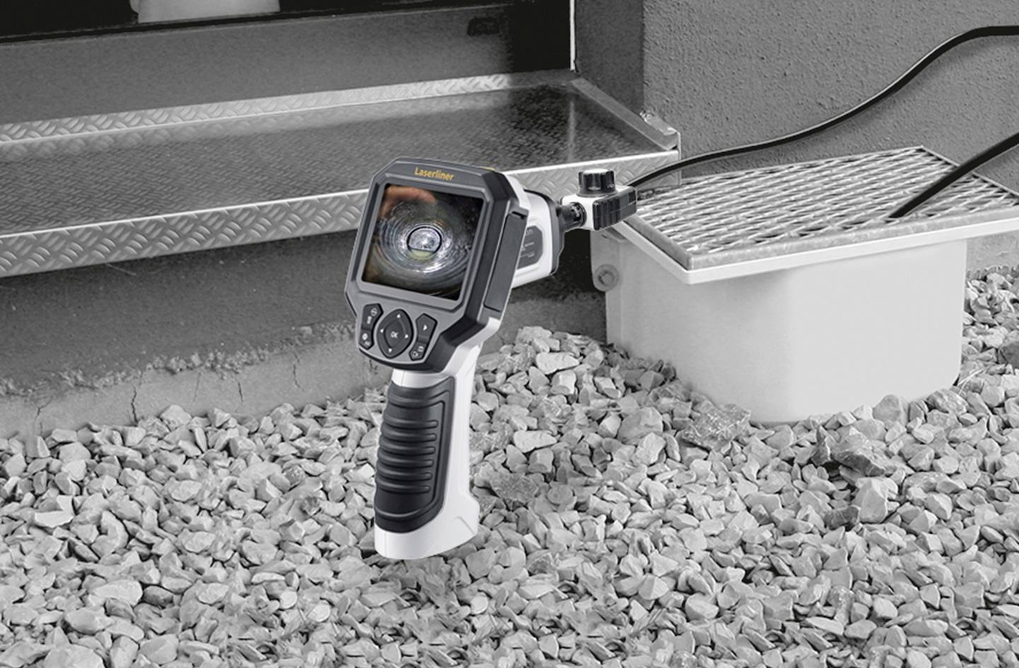 Handapparaat met scherm scant buizen; omgeving met puin.