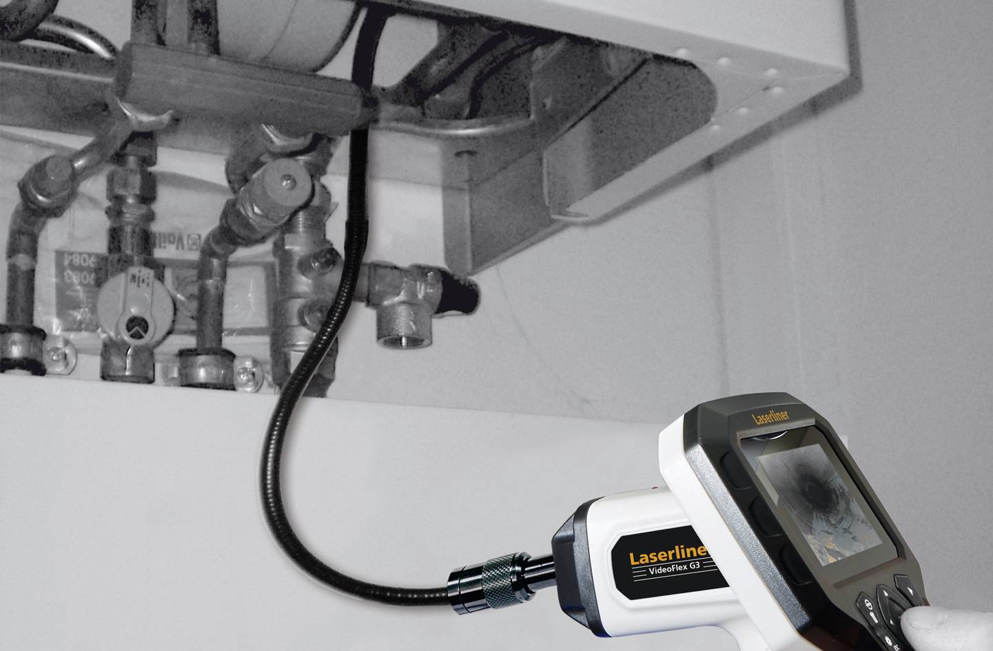 Een installateur inspecteert met een endoscoop de buizen van een verwarmingsketel om lekken of schade te controleren.