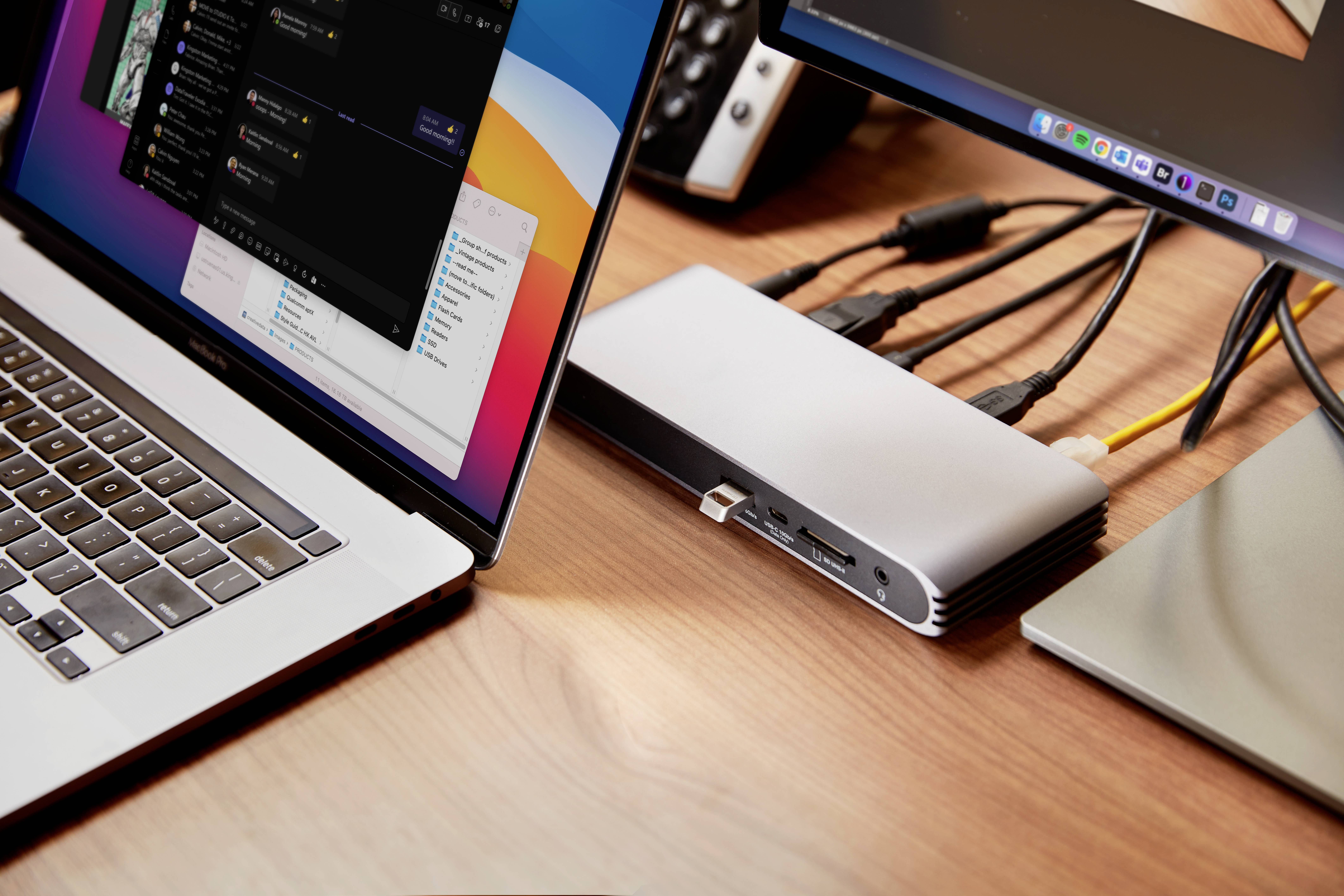 Laptop en monitors op een bureau, verbonden via een USB-C-hub. De hub heeft meerdere kabels en aansluitingen.