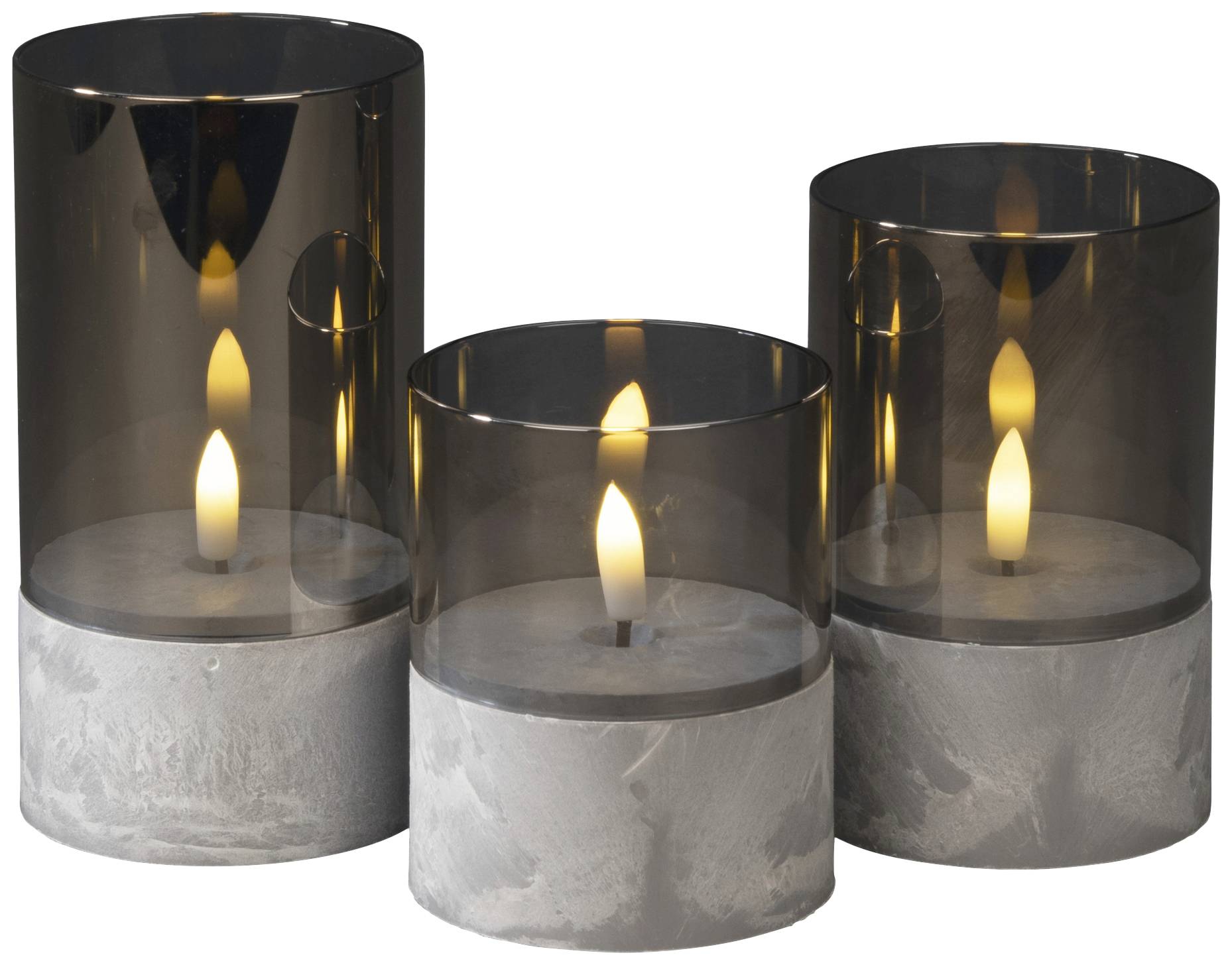 Drie decoratieve kaarsen met een grijze glazen kap en betonnen voet. De vlammen branden rustig en gelijkmatig, creëren een gezellige sfeer.