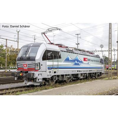 Een goederentreinlocomotief van SBB Cargo International staat op een spoorrails. De locomotief vertoont kleurrijke bergmotieven aan de zijkant.