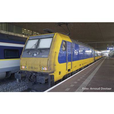 Een geel-blauwe trein van de NS staat op het spoor van een station. Op de achtergrond zijn een ander spoor en de stationsstructuren zichtbaar.