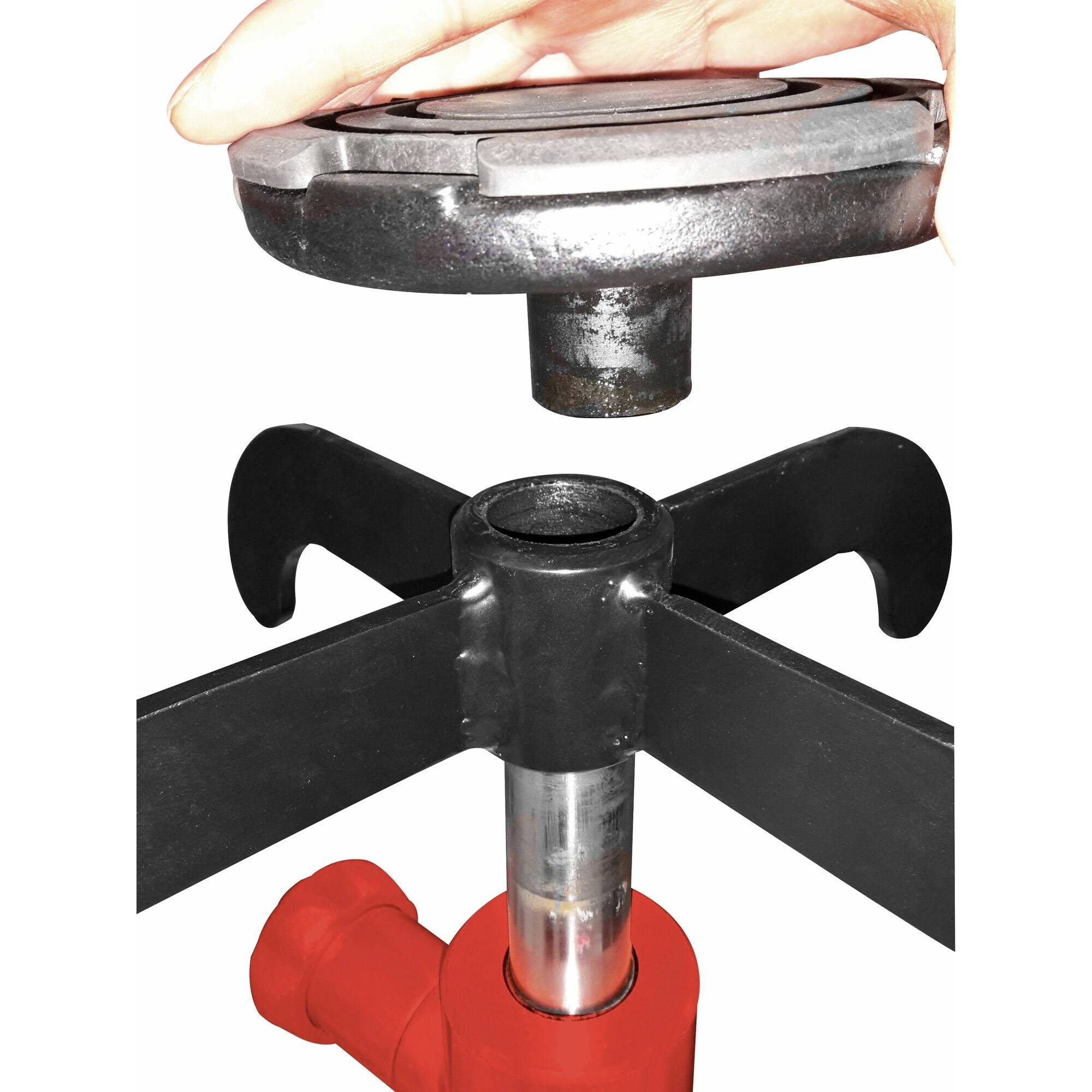 Een hand houdt een metalen onderdeel vast boven een ander gereedschapsdeel met een haak en een rode sokkel.