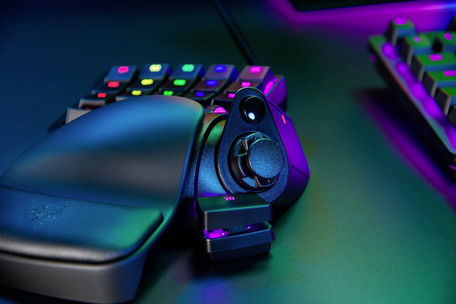 Een gamingtoetsenbord met gamepad en verlichtingseffecten in verschillende kleuren op een bureau.