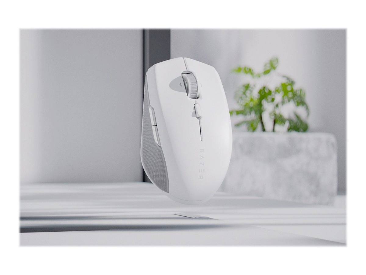 Een zwevende witte computermuis in een minimalistisch ingericht vertrek met een plant op de achtergrond.