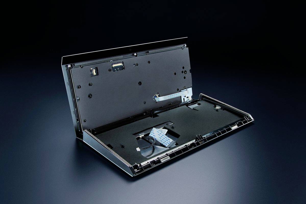 Een geopend elektronisch apparaat met zichtbare aansluitingen en kabels, op een donkere achtergrond.