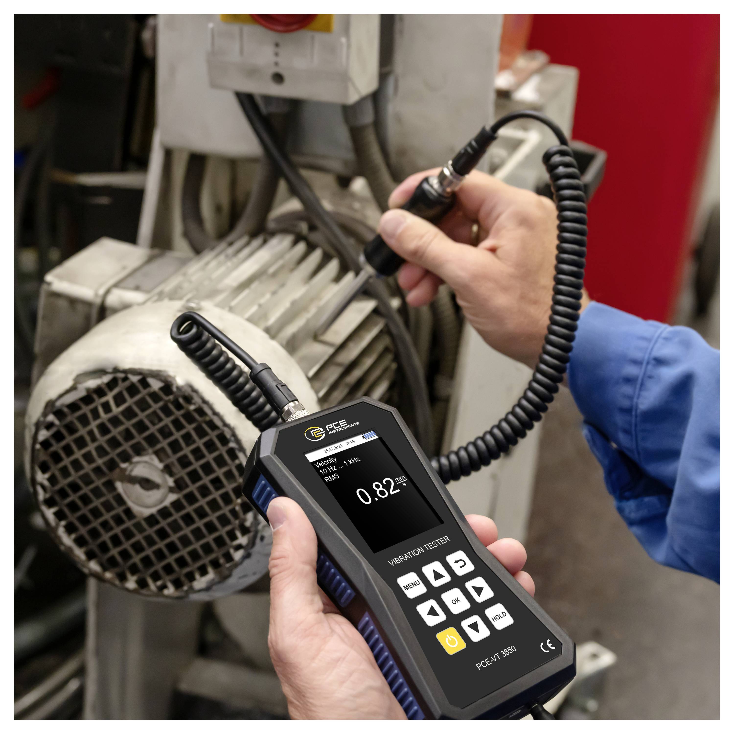 Technicus die een handheld trillingmeter op een elektromotor gebruikt om machinetrillingniveaus tijdens onderhoud te meten.