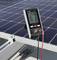 Digitaal meetapparaat toont waarden van zonnepaneel. Meetapparaat aangesloten op schuin geplaatst zonnepaneel met kabels. Meetwaarden afleesbaar.