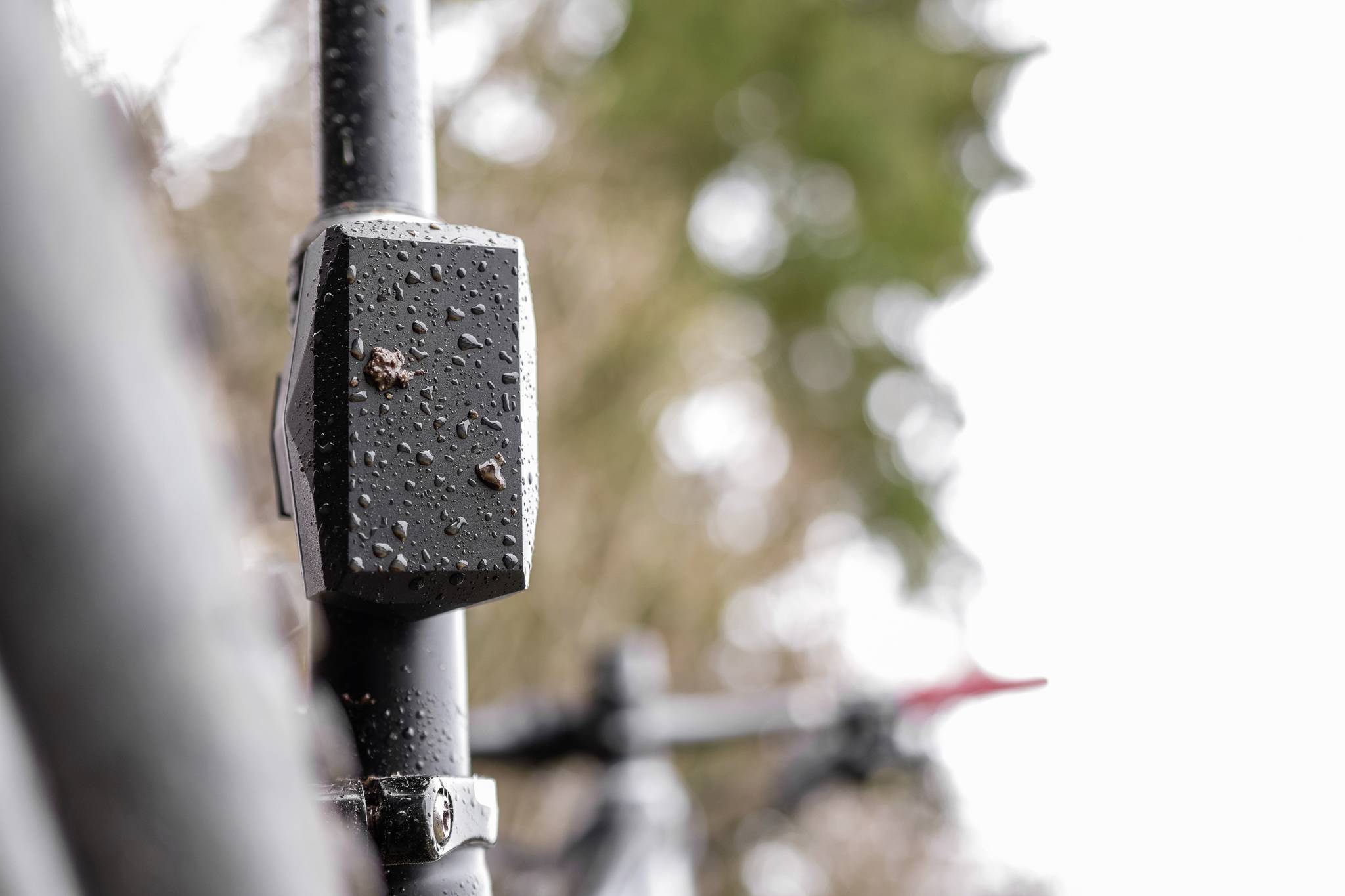 Close-up van een fiets met regendruppels op het metalen frame, met een wazig groene landschap op de achtergrond.