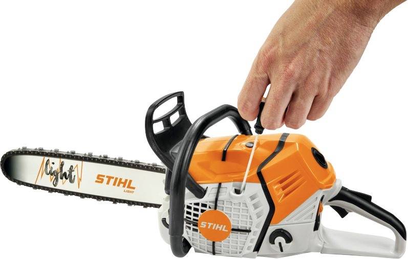 Een hand trekt aan het starttouw van een oranje-witte Stihl-kettingzaag.