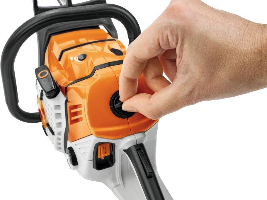 Hand die de vergrendelingsknop van een oranje-zwarte motorzaag draait.