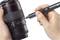 Een persoon houdt een cameralens in de hand en gebruikt een klein gereedschap om aan de schakelaars van de lens te werken.
