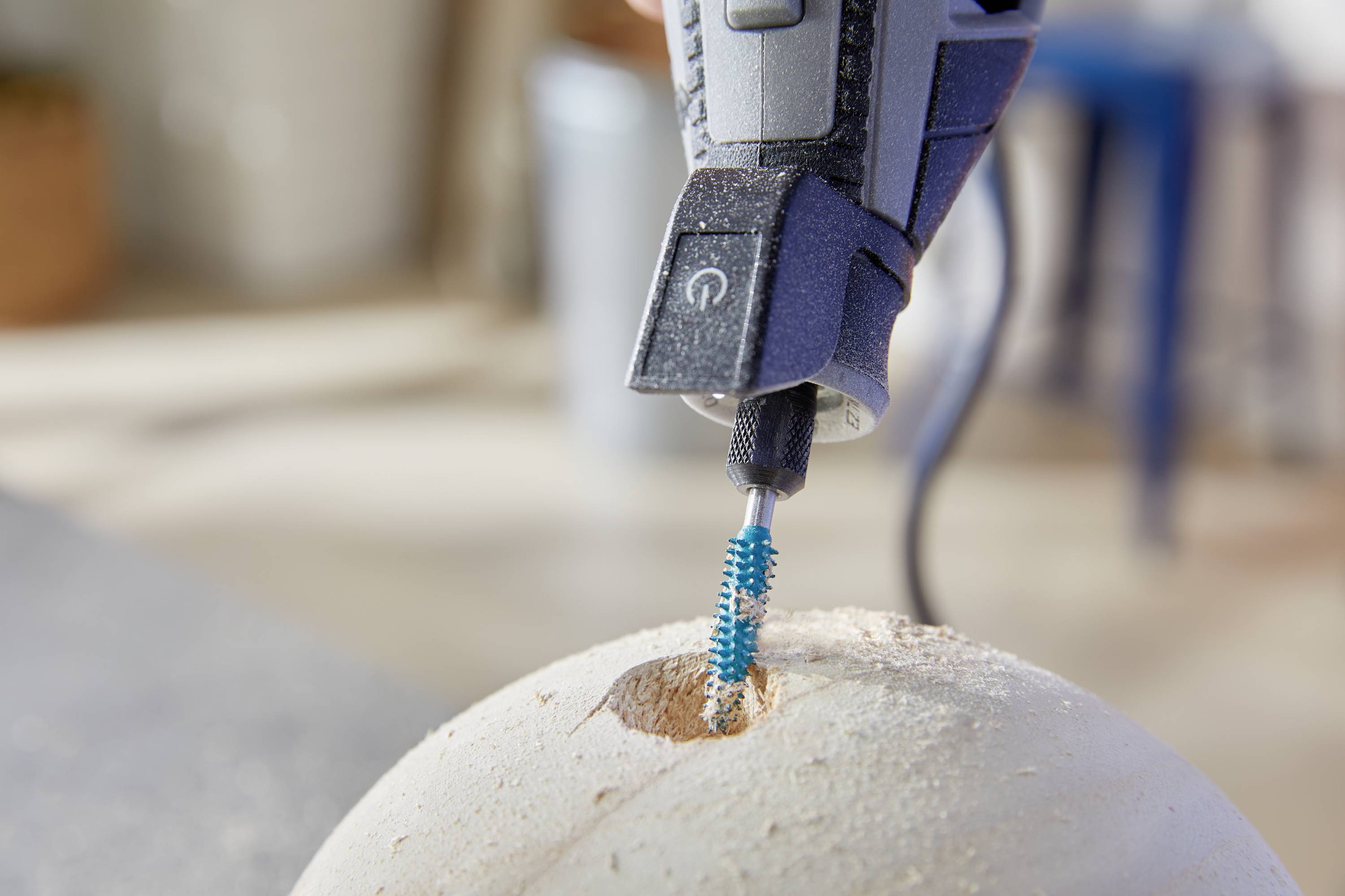 Een close-up toont een roterend gereedschap dat een gat boort in een lichte, bolvormige oppervlakte.