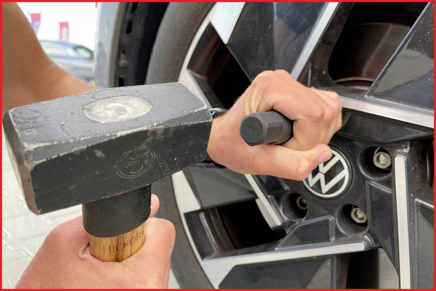 Een persoon draait met een sloophandaanhamer en een speciaal gereedschap de wielmoer van een autoband vast.