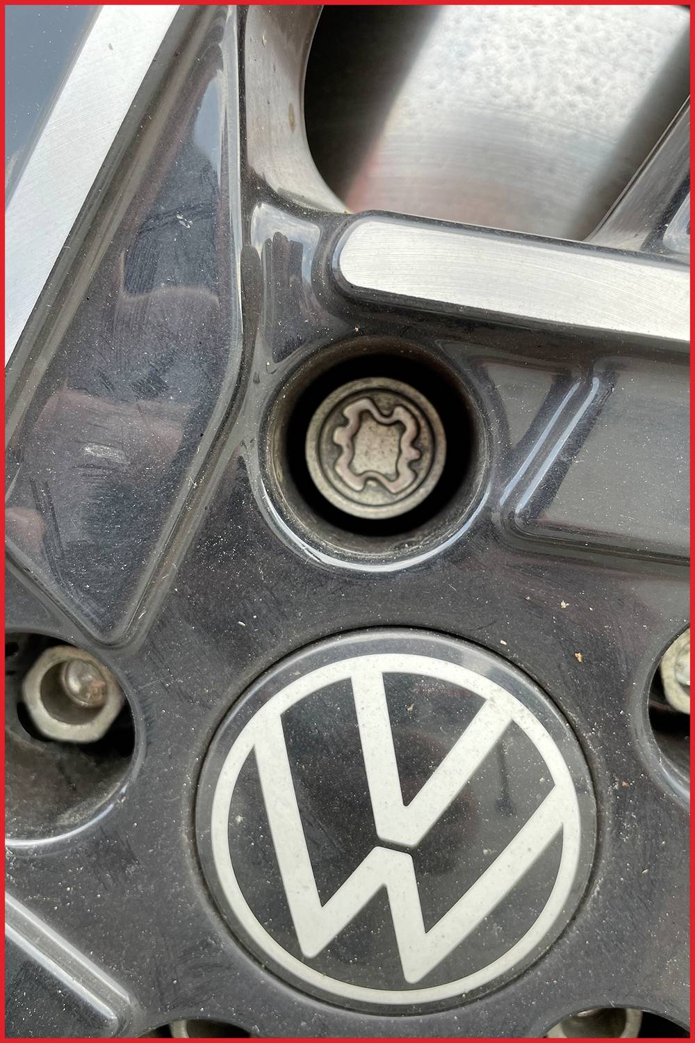 Close-up van een VW-logo op een autowiel, met een centrale wielnaafsleutel zichtbaar in het bovenste deel.