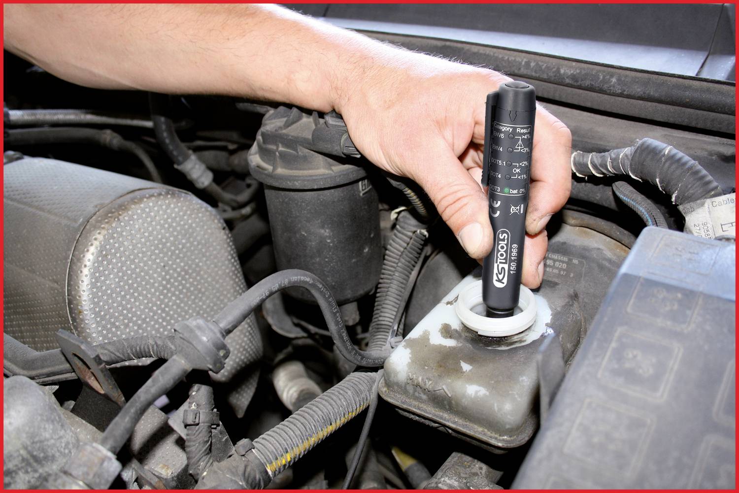 Een hand houdt een elektronisch testapparaat vast en controleert de remvloeistof in een auto.