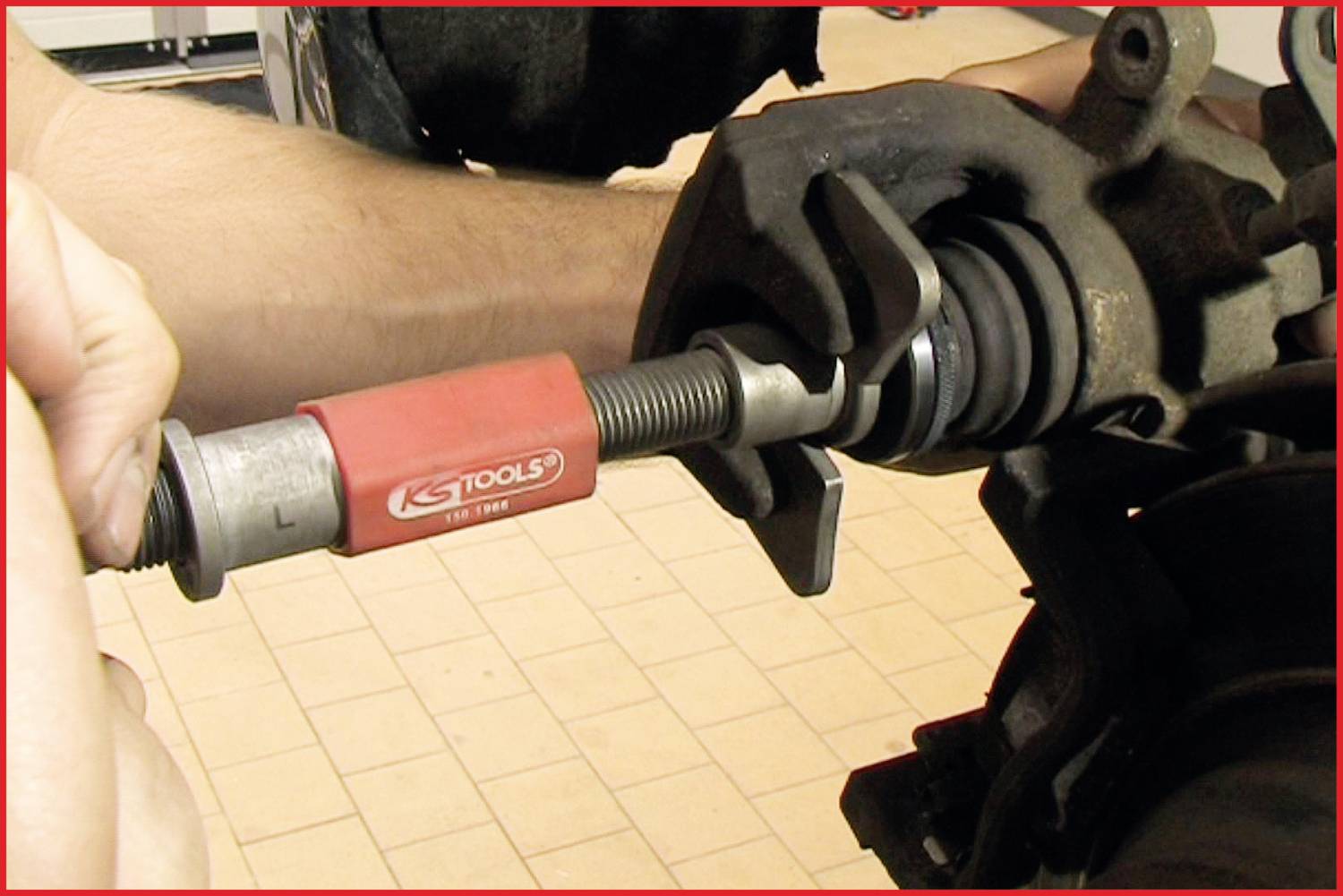 Een monteur gebruikt een speciaal gereedschap om de wiellagering van een voertuig te verwijderen.