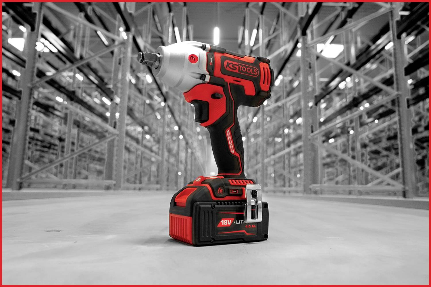 Accuschroefboormachine met rood en zwart design staat centraal in een lege opslagloods met rekken op de achtergrond.