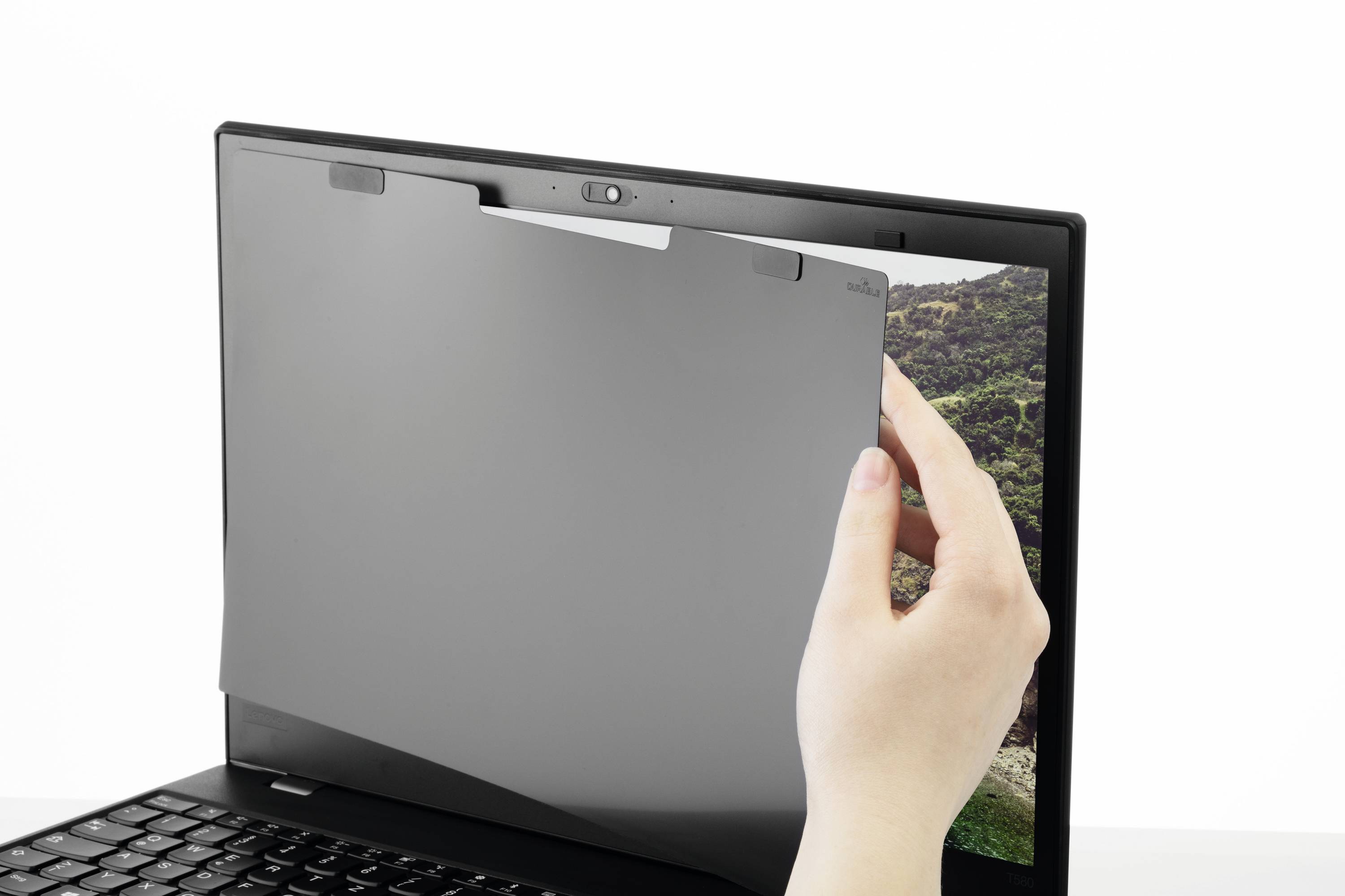 Een privacyfilter wordt door een hand op het scherm van een laptop aangebracht. De filter beperkt de kijkhoek op het scherm.