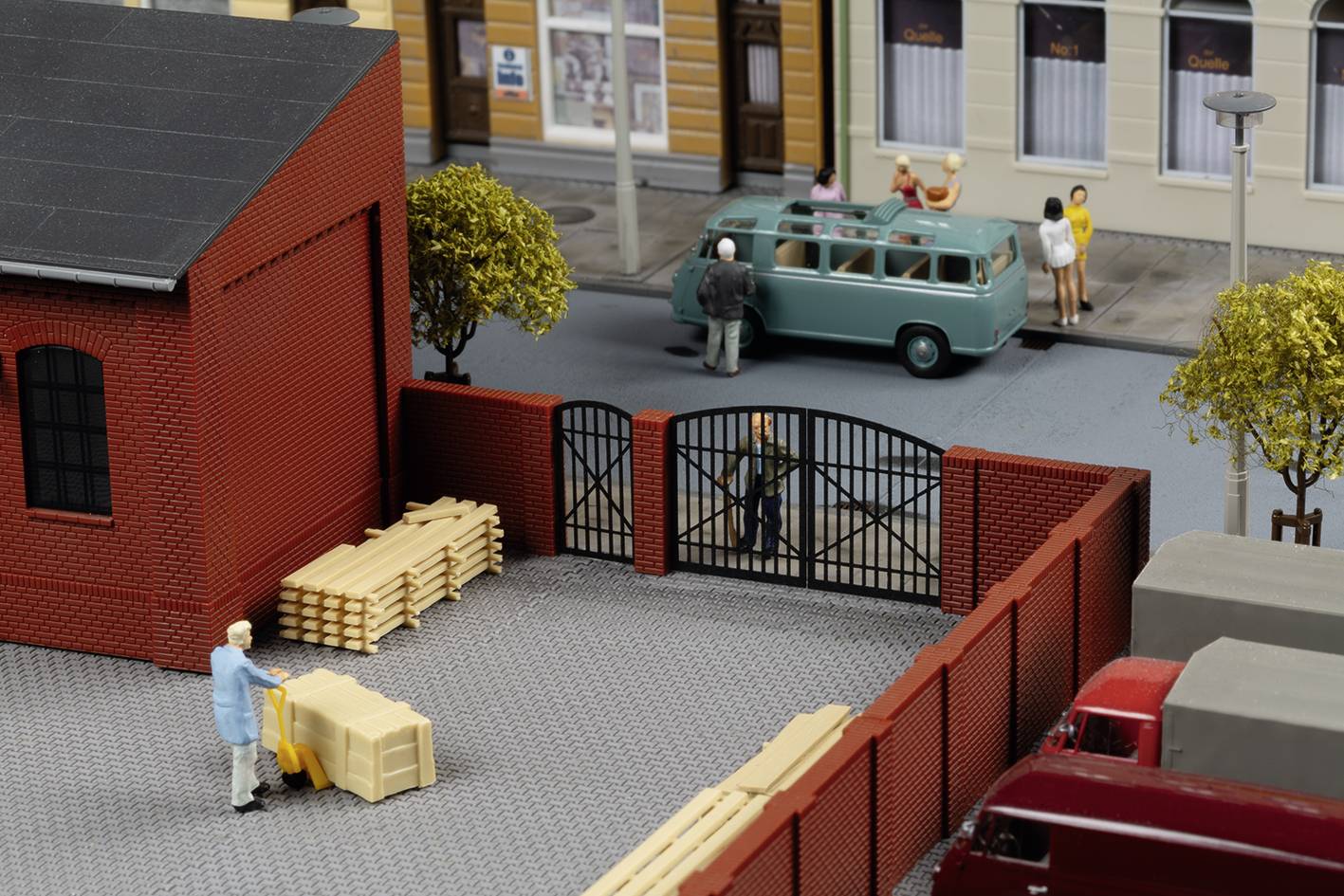 Een miniatuurmodel toont een man die een pallet vervoert in een magazijnruimte, terwijl op de achtergrond een bestelwagen geparkeerd staat op straat.
