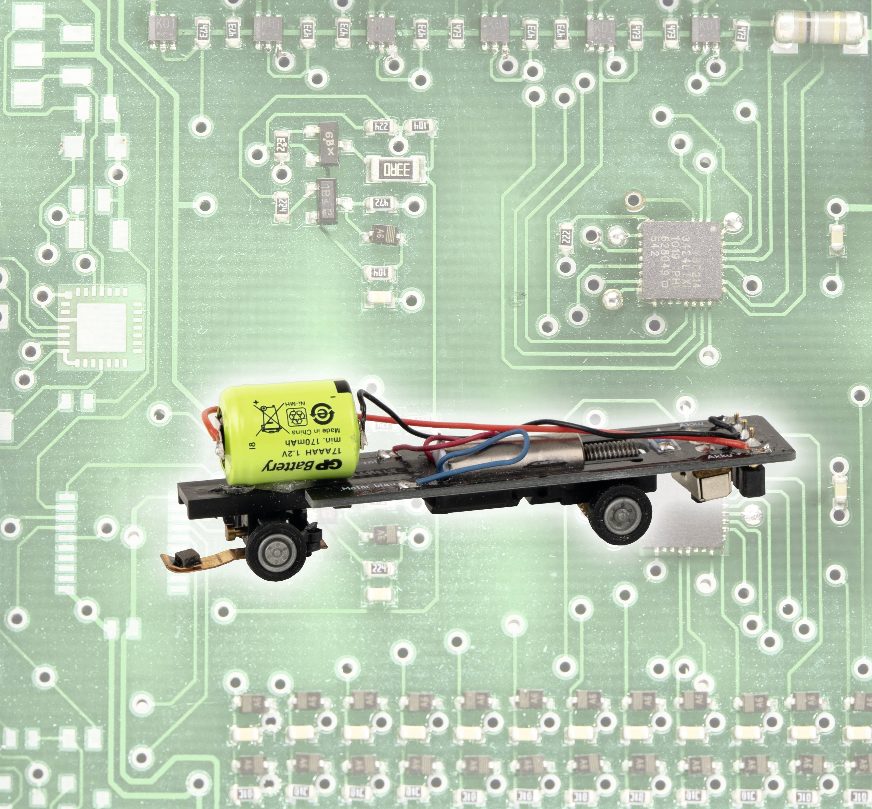 Een modelbaan-decoder met kabels en een gele condensator is gemonteerd op een groene printplaat.