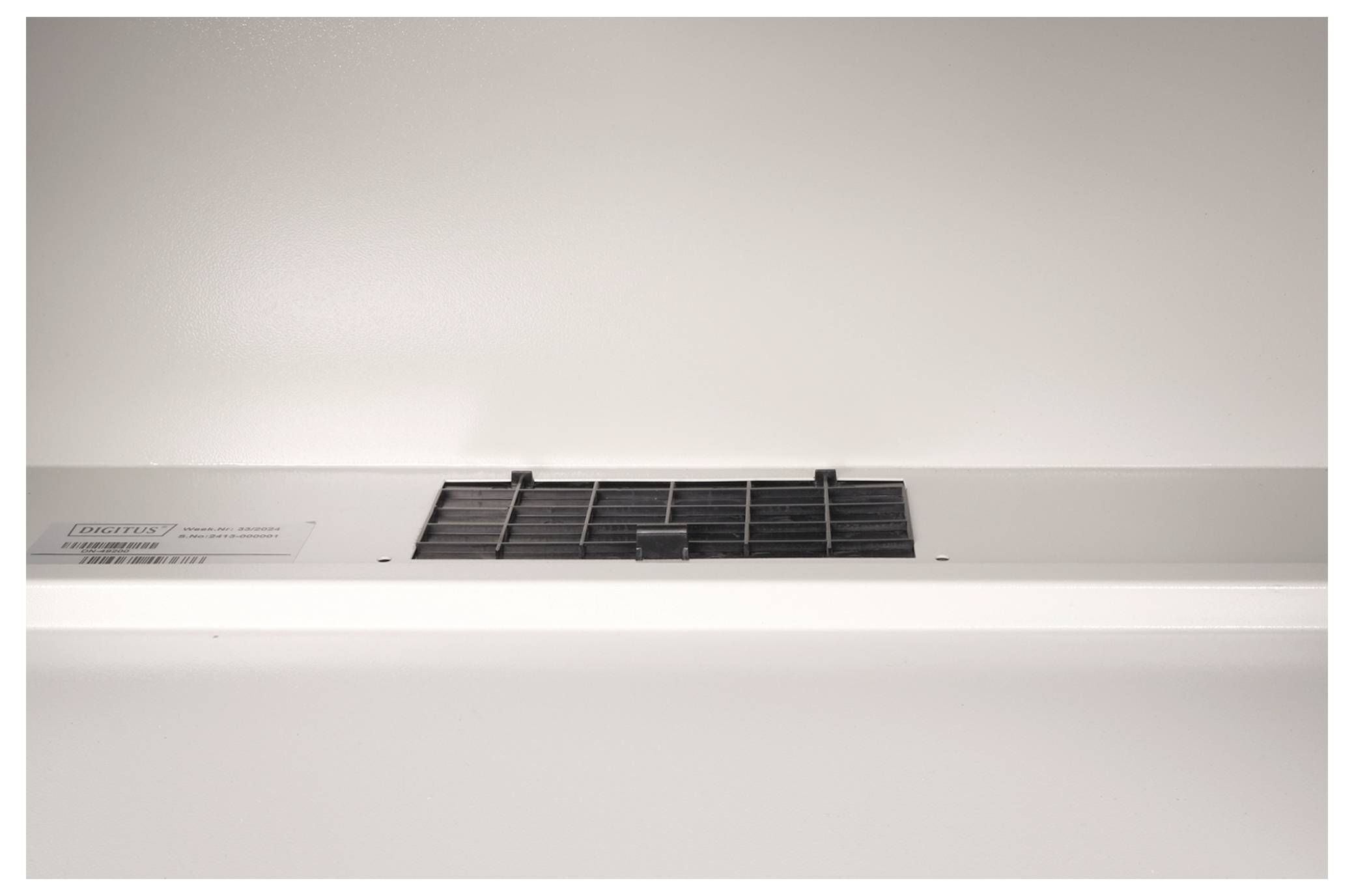 Onderaanzicht van een afzuigkap met een rechthoekige opening en zwart rooster in een witte keuken.