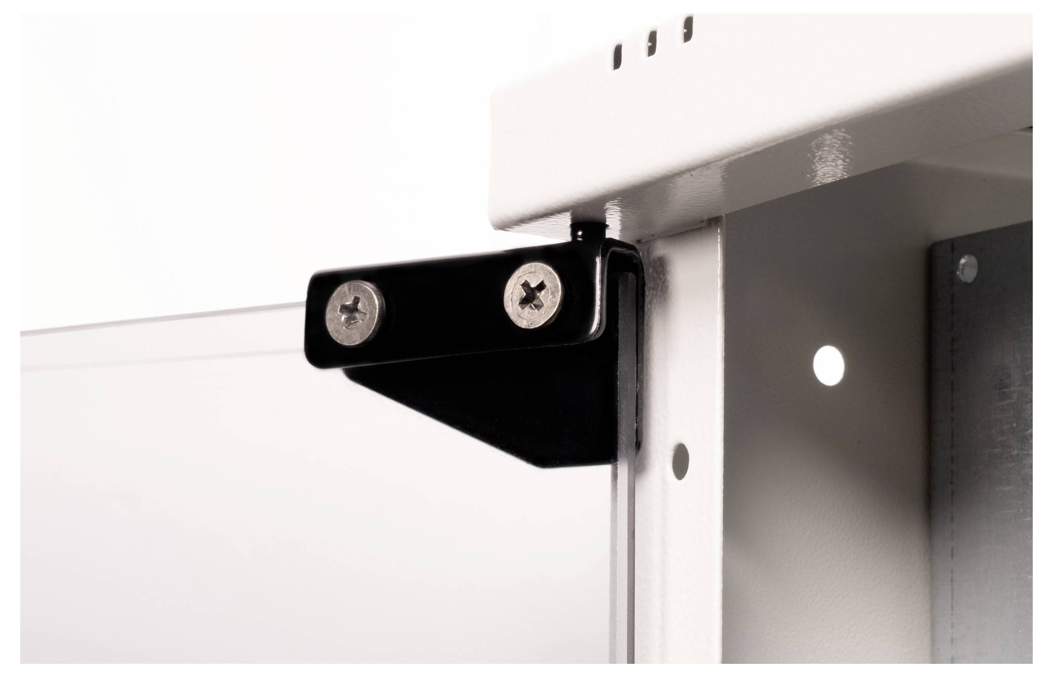 Een zwart metalen hoekelement met twee zichtbare schroeven bevestigt een witte metalen plaat aan een frame.