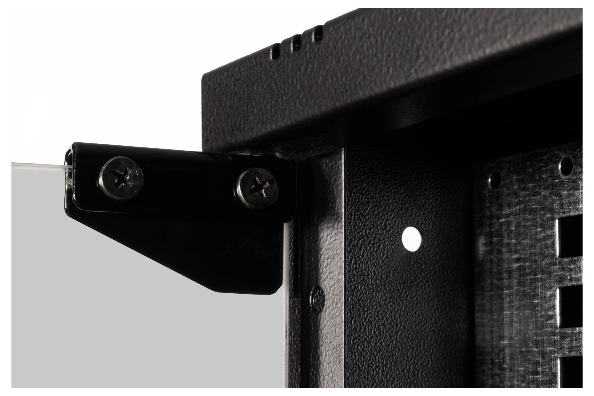 Close-upfoto van een zwarte metalen hoek die met twee schroeven aan de hoek van een frame is bevestigd.