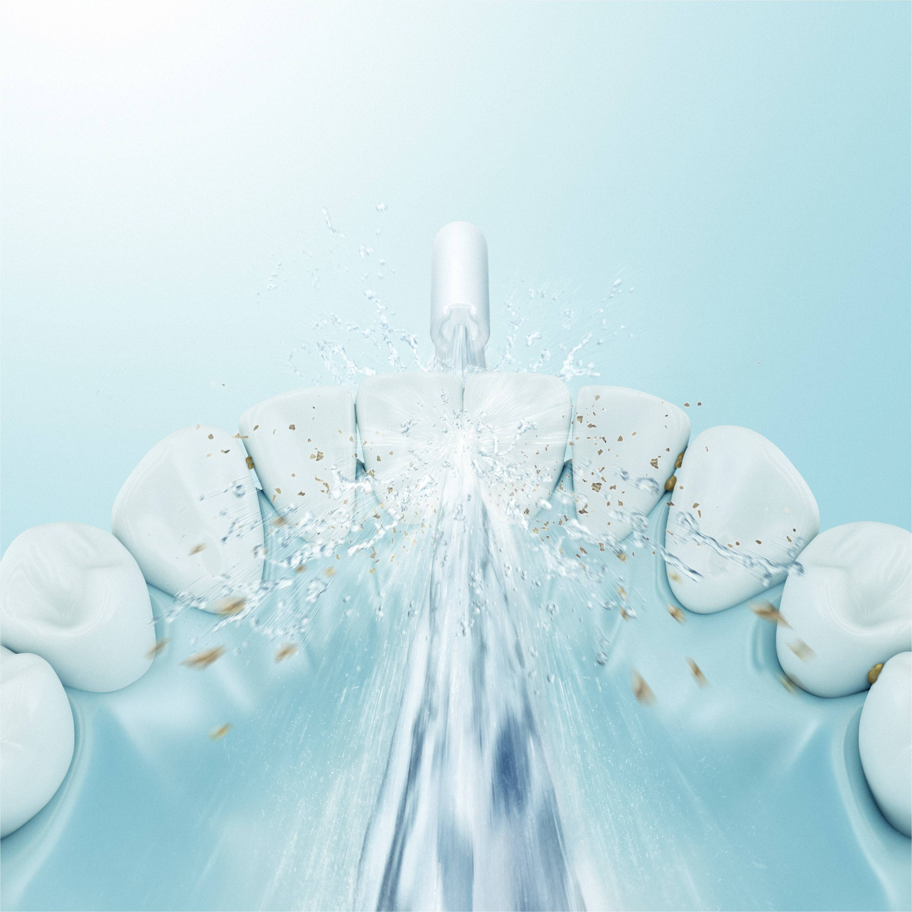 Een tandenborstel spuit water in high-speed opname om tandplak te verwijderen van witte tanden, tegen een lichtblauwe achtergrond.