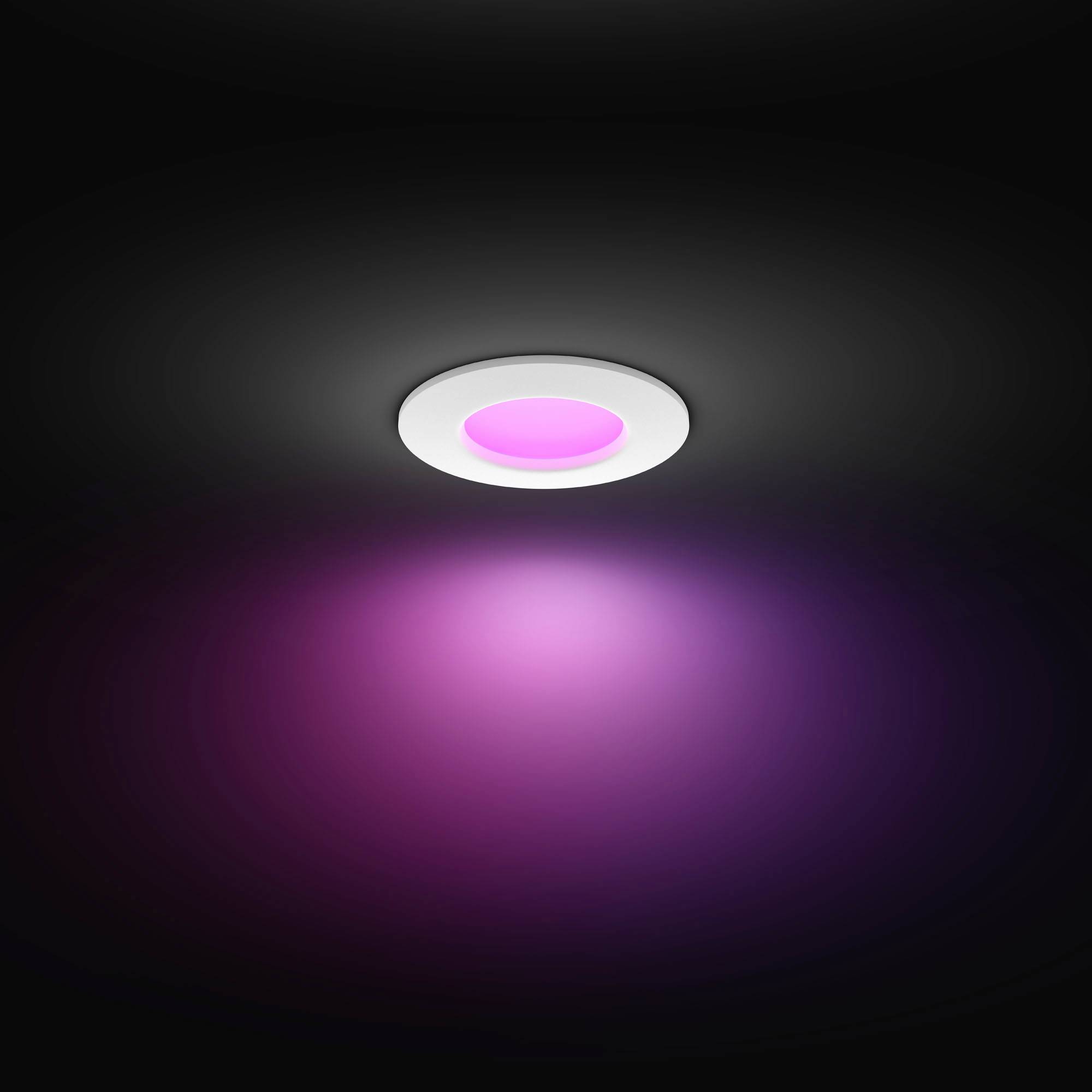 Een ronde plafondlamp straalt paars licht uit. Ze zorgt voor een zachte, gekleurde verlichting in een donkere ruimte.