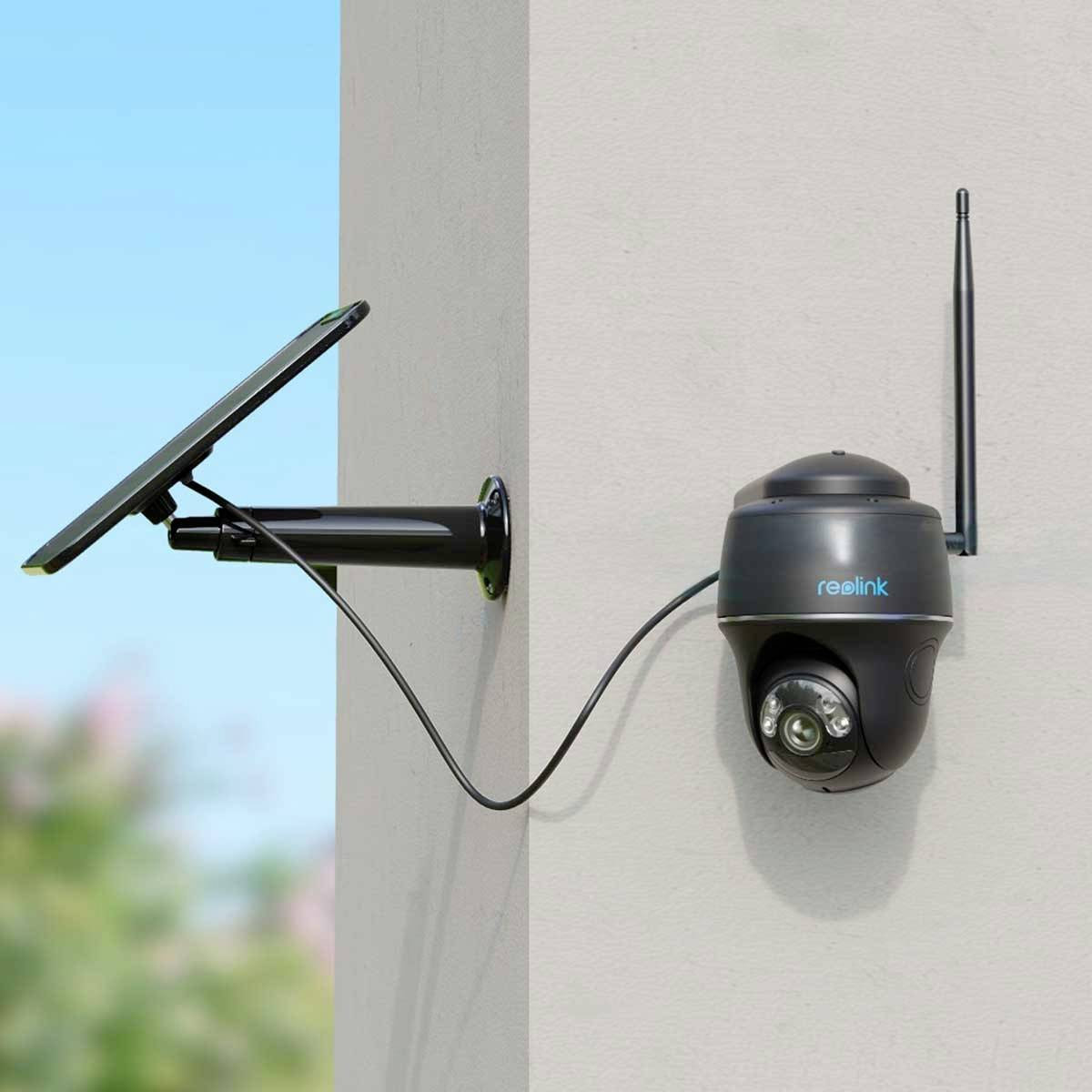 Een bewakingscamera met zonnepaneel is aan een muur bevestigd. De camera is voorzien van een antenne en verbonden met het zonnepaneel.