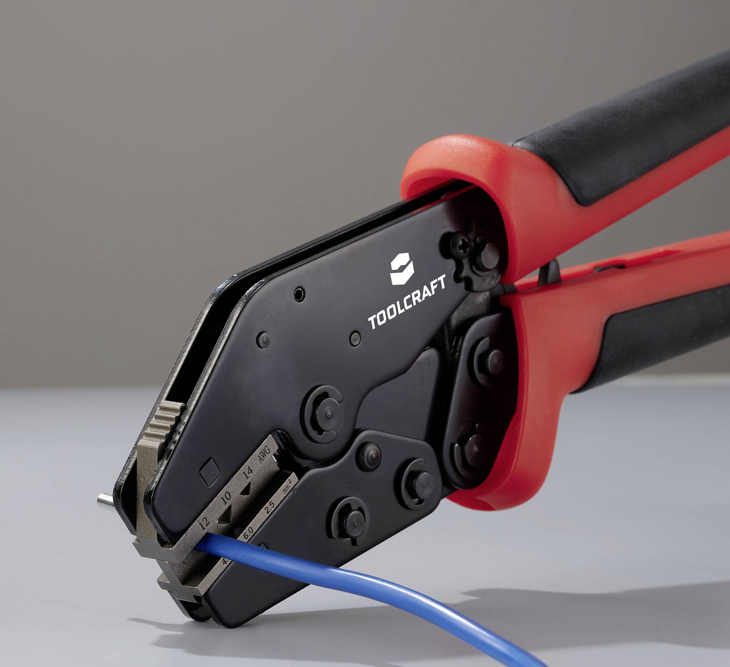 Een krimptang met het opschrift 'TOOLCRAFT' op de tang, die een blauw kabel vasthoudt. De handgrepen zijn zwart en rood.