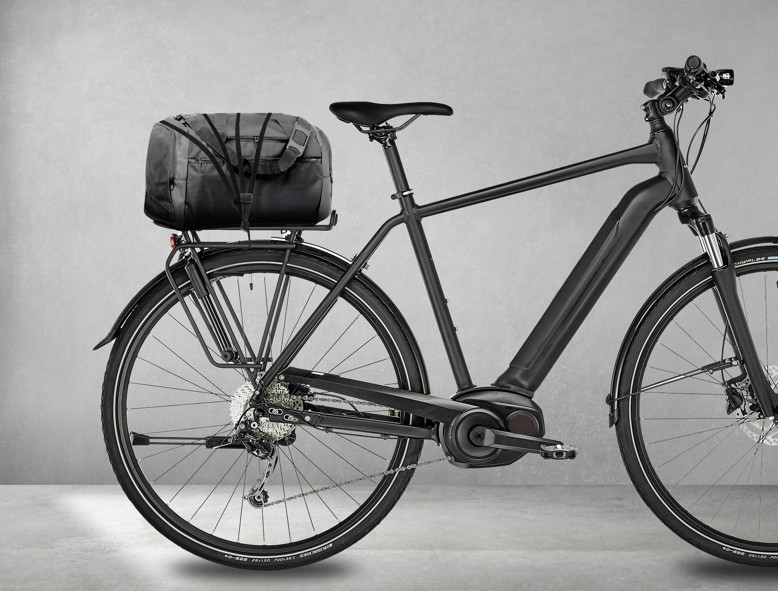 Een zwarte elektrische fiets met bagagedrager en gemonteerde tas op een grijze achtergrond.