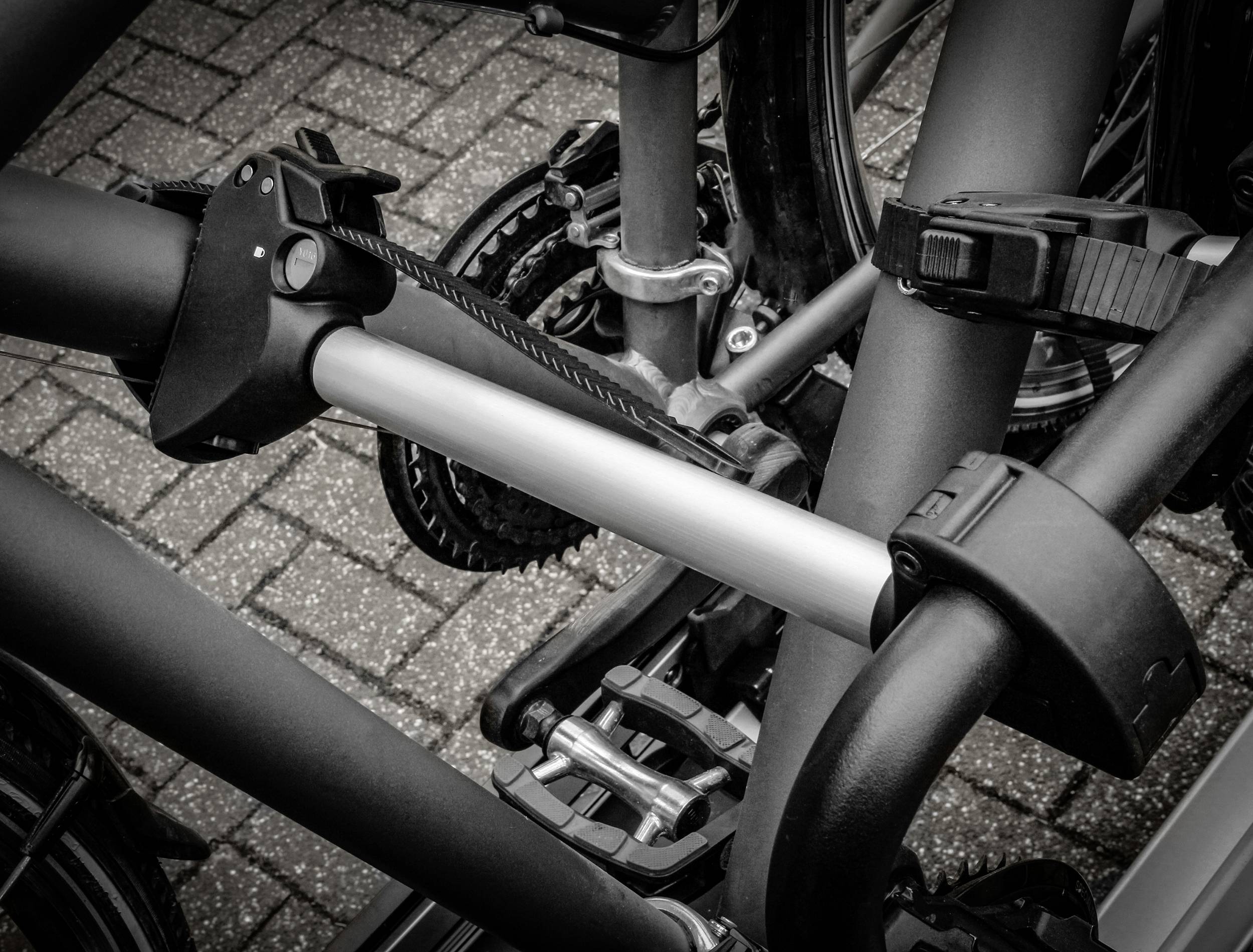 Close-up van een fietsendrager die meerdere fietsen vasthoudt, gemonteerd op een voertuig met beveiligde frames en pedalen.