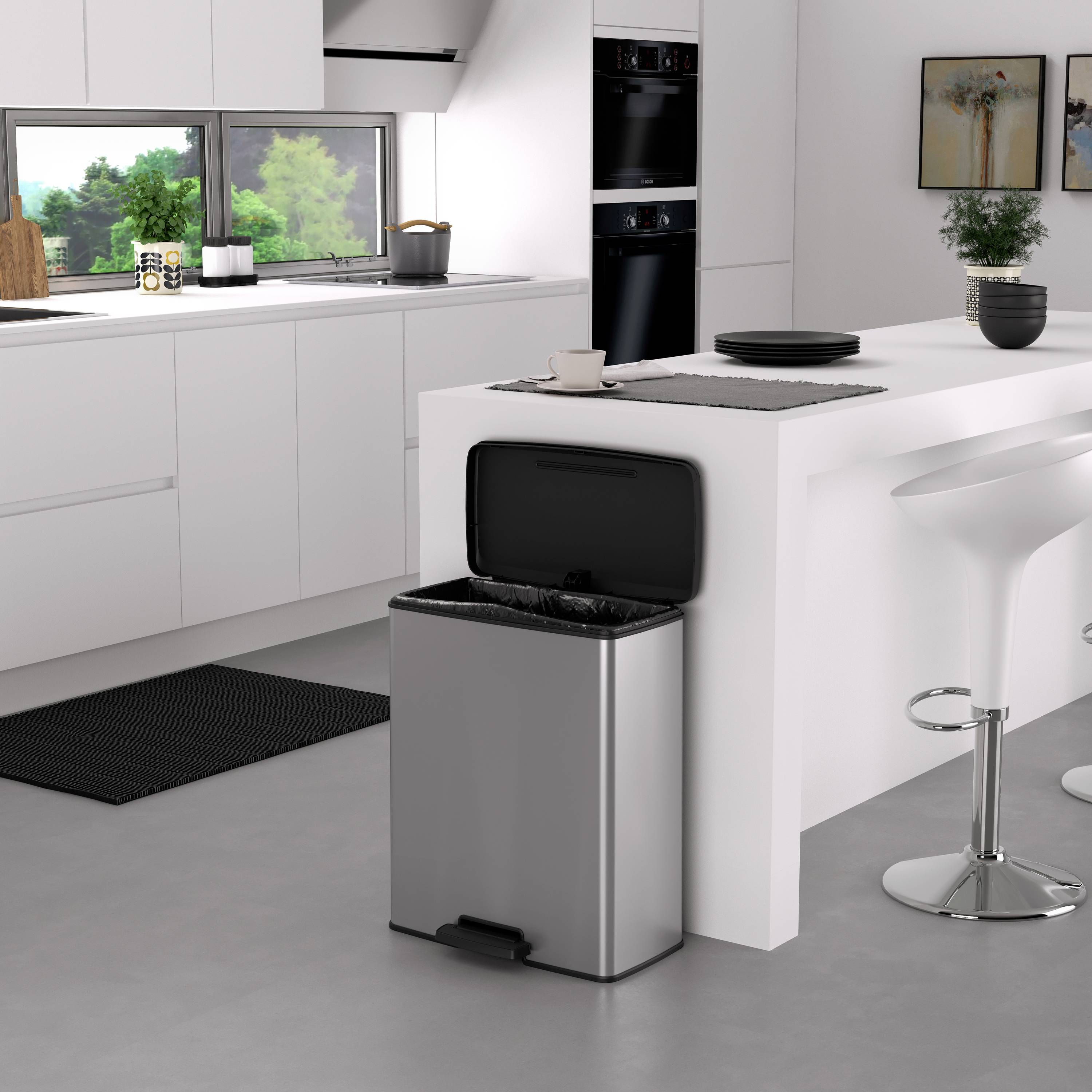 Moderne keuken met witte kasten, een groot keukeneiland met twee barkrukken en een openstaande prullenbak op de voorgrond.