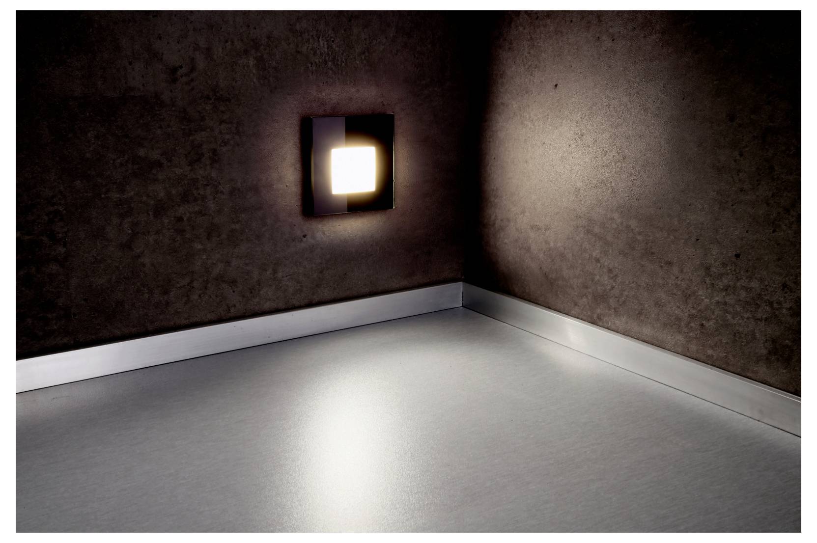 Lege kamer met bruine muren en een heldere wandlamp, die een weerspiegeling op de grijze vloer creëert.