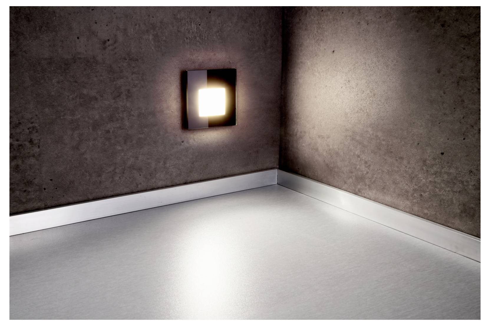 Lege hoek van een kamer, verlicht door een vierkante wandlamp, met grijze muren en witte vloerlijsten.