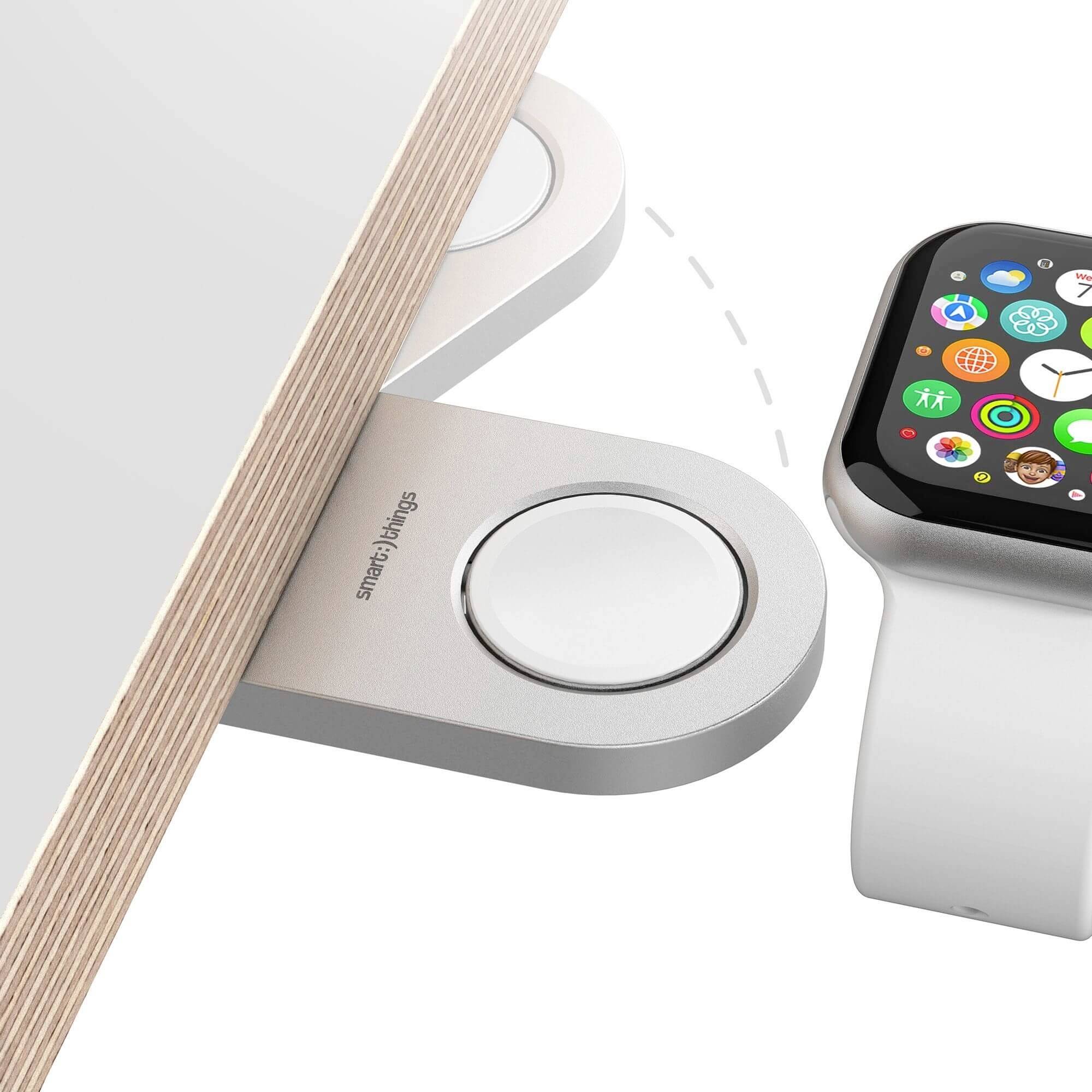 Een Apple Watch wordt opgeladen op een magnetisch oplaadstation op een tafel van licht hout.