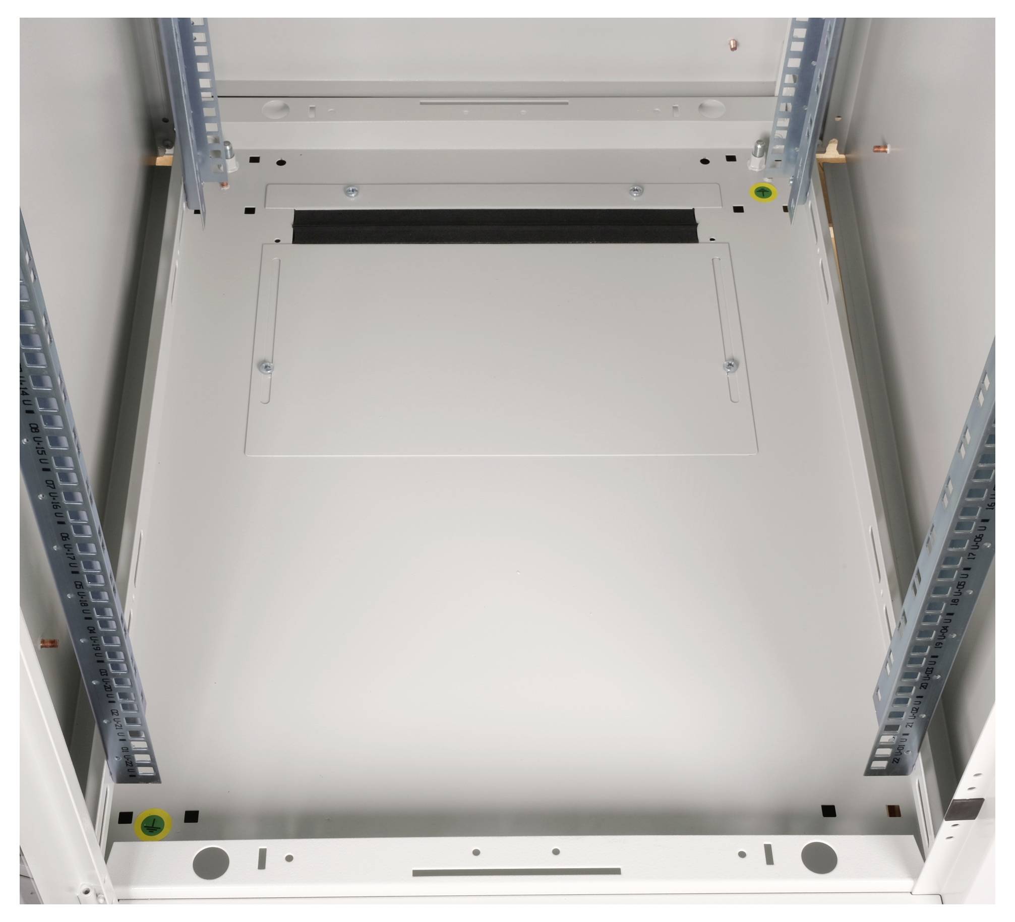 Metalen binnenkant van een lege schakelkast met montagerails aan de zijkanten en kabelopeningen bovenaan.