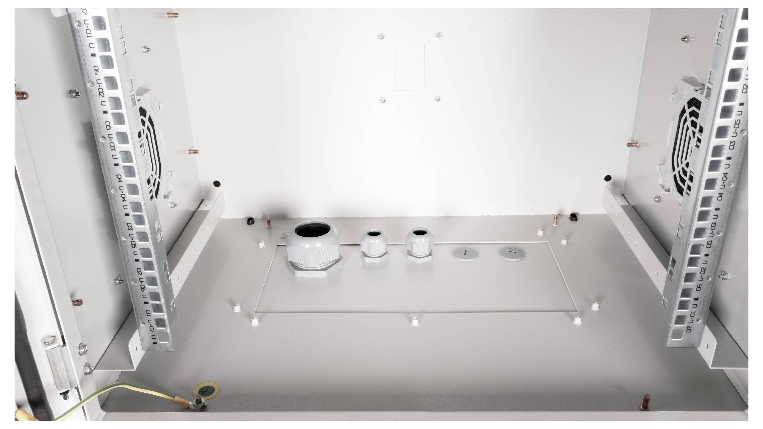 Binnenaanzicht van een leeg metalen behuizing met ventilatoren aan de zijkanten en verschillende kabelinvoeren aan de onderkant.