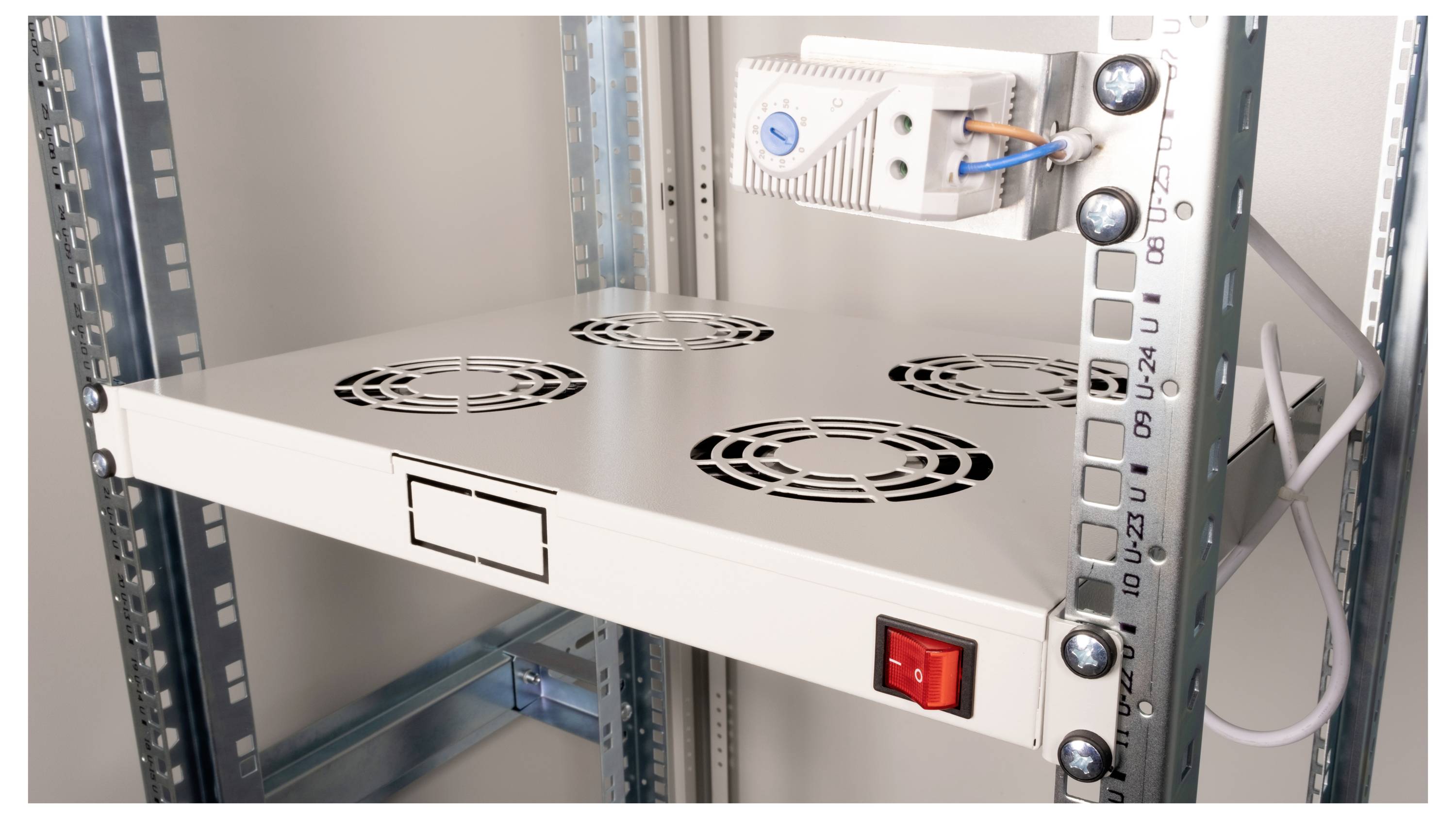 Metalen rek met ventilatoren voor ventilatie en een rode schakelaar in een serverruimte.