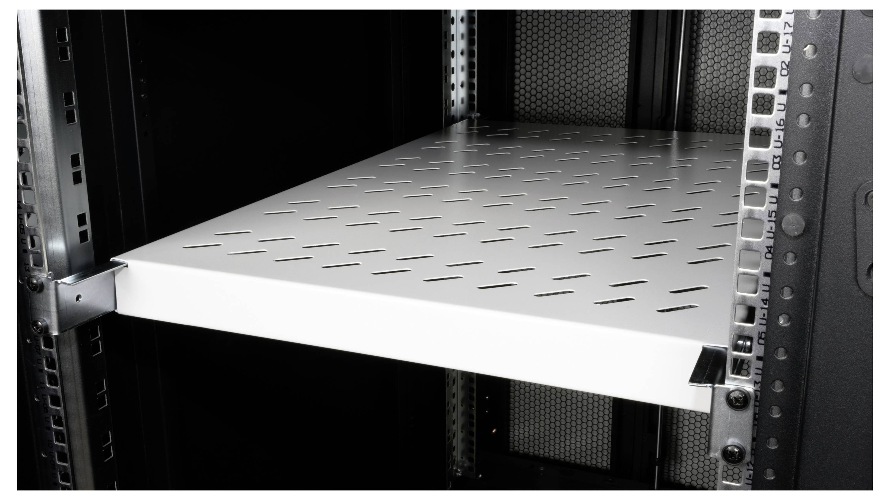 Een leeg metalen schap in een serverrek. Het schap is zilverkleurig, geperforeerd en bevestigd tussen de rekrails.