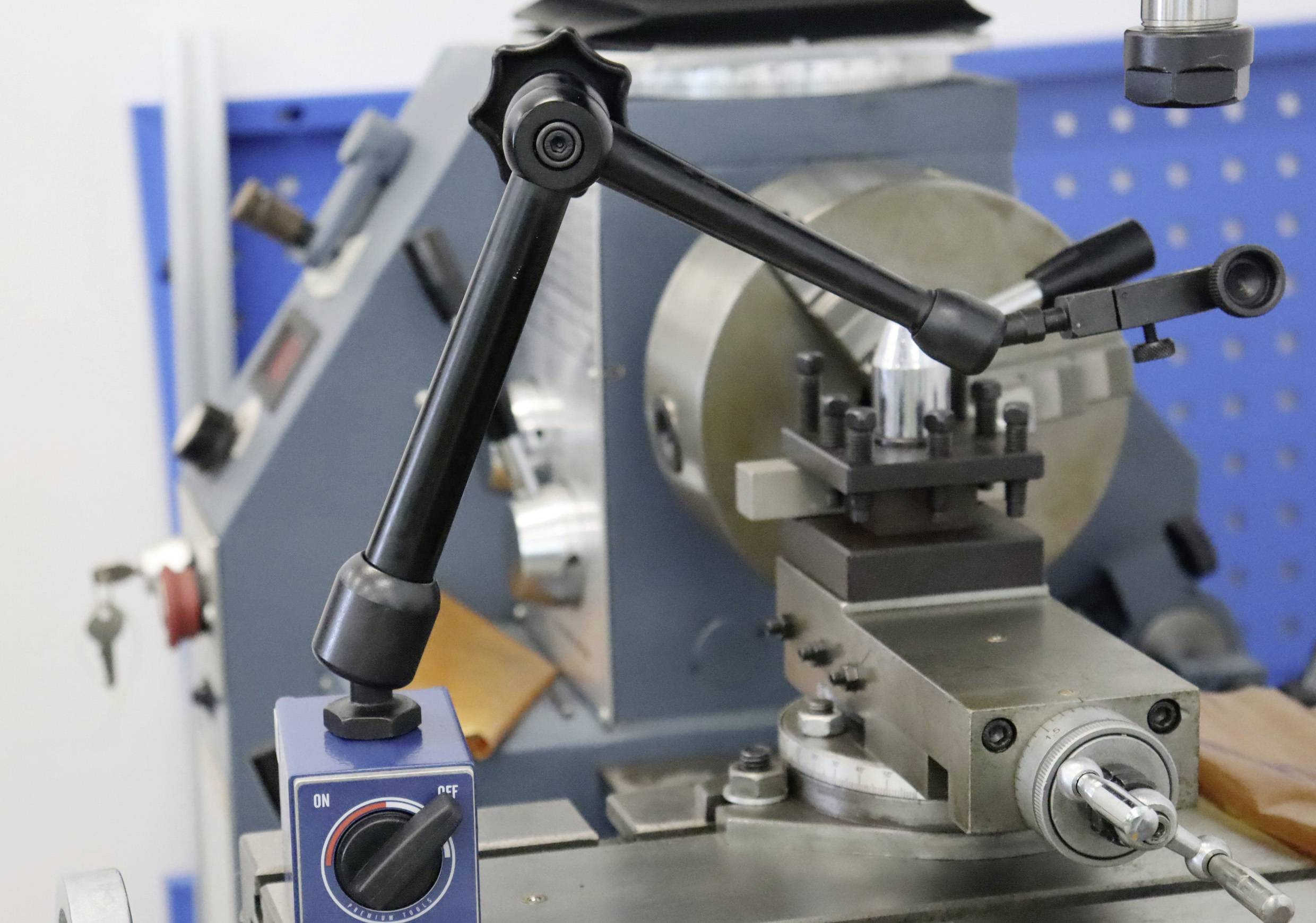 Een draaibank met bedieningselementen op de voorgrond die nauwkeurig machinaal werk mogelijk maken. Links een blauwe schakelaar met schaal.