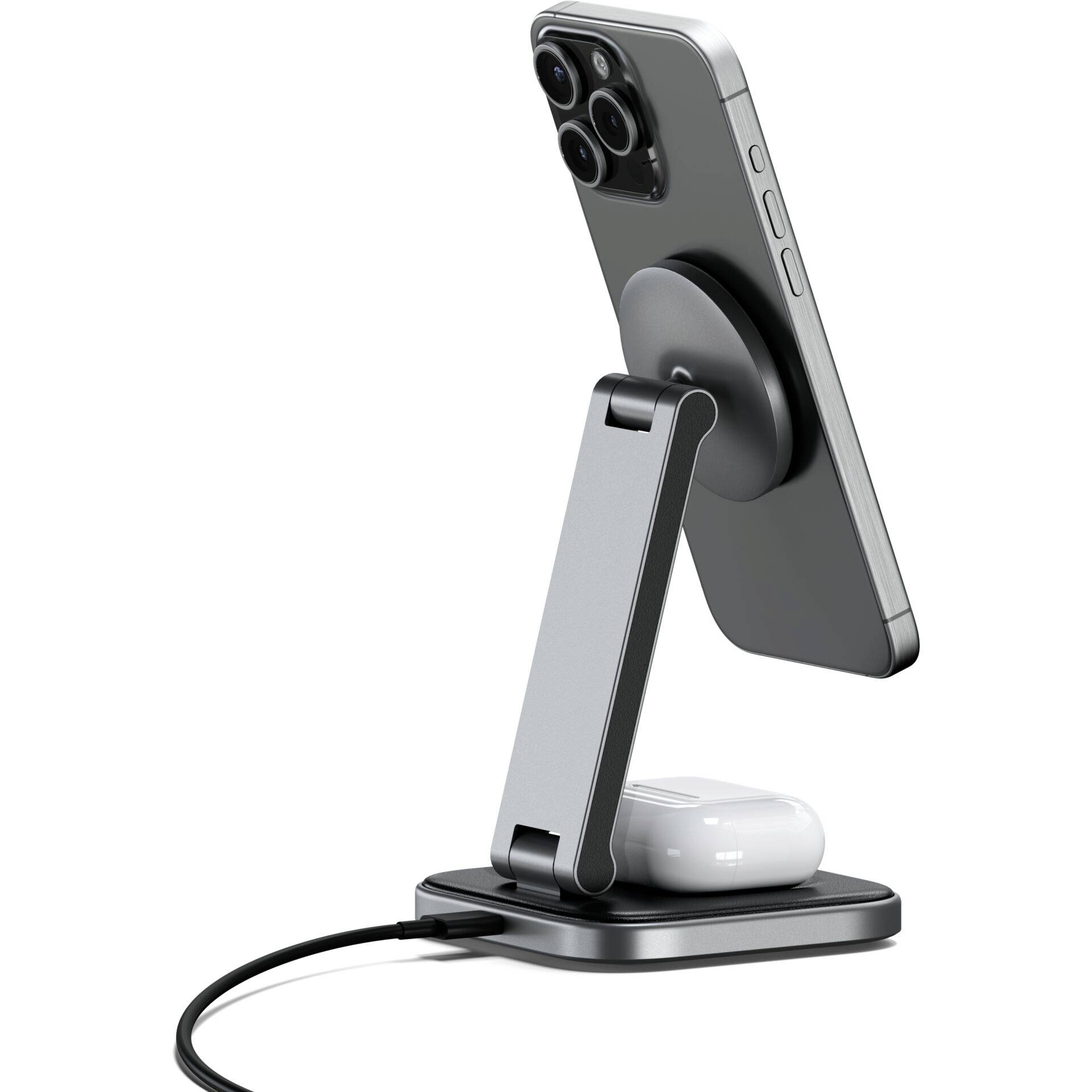 Een smartphone staat scheef in een metalen laadstation. Eronder liggen draadloze oordopjes, eveneens opgeladen.