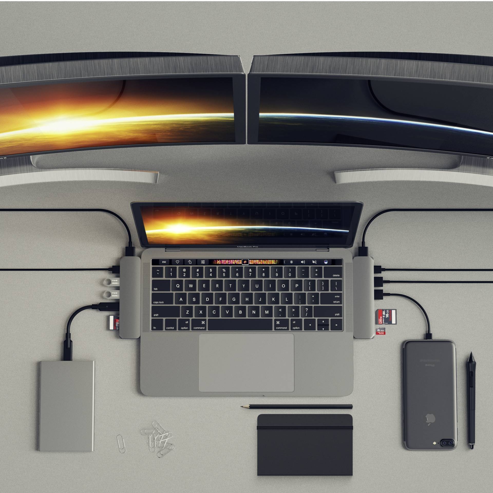 Een moderne werkplek met een laptop, twee monitoren, een smartphone, een externe harde schijf en schrijfbenodigdheden.