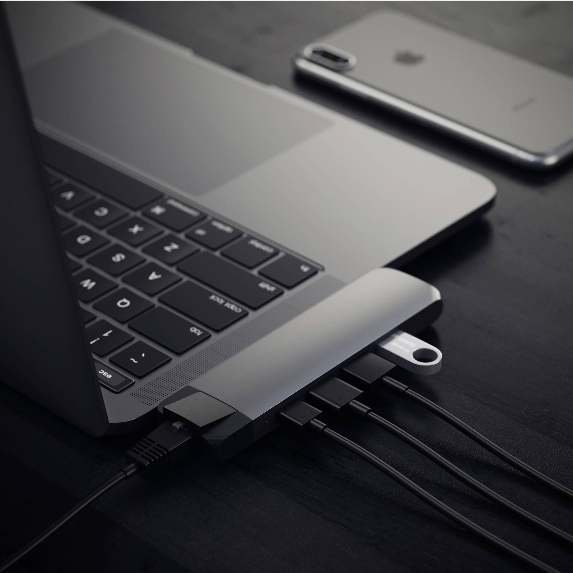 Een laptop met meerdere USB-apparaten aangesloten via een hub, naast een smartphone op een tafel.